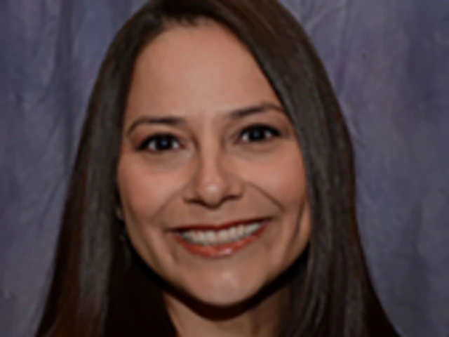 Woman with straight brown hair smiling in front of a gray backdrop