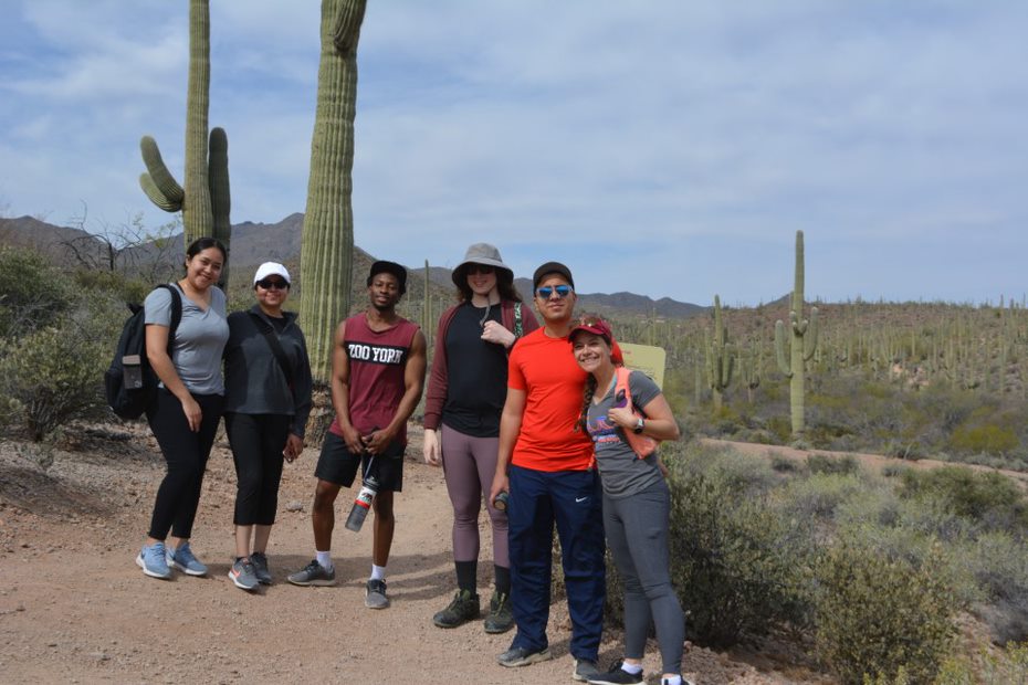 five young individuals standing in the desert under a sunny sky