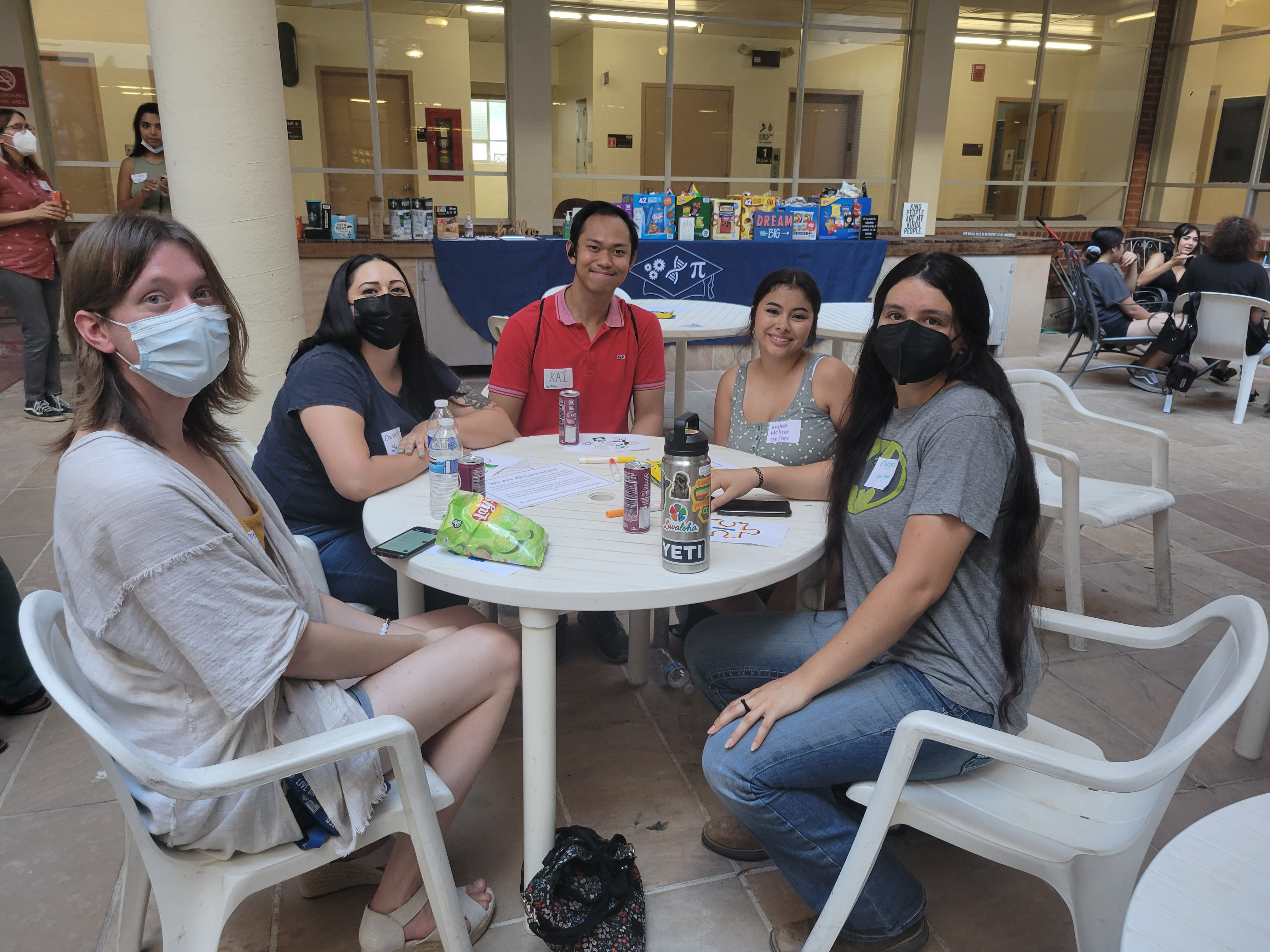 five students sitting around a table in a patio