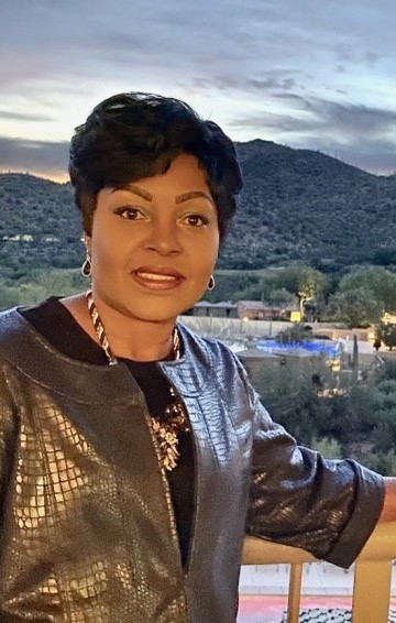 Tamara Carter, african american woman wearing a shimmery blazer, short black hair, mountain scene in the background