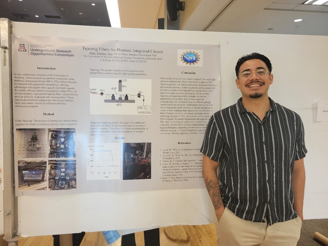 male student wearing a short sleave striped shirt standing in front of a poster board presentation